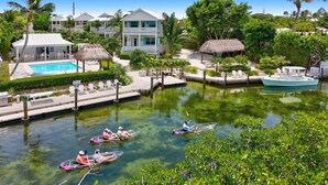 A resort with a swimming pool, a boat dock, and a waterway with canoes. - Isla Lychee: Boutique Resort, FREE Boat Dockage Sep-Oct Only! (Islamorada)
