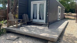 A compact, dark-colored cabin with a sliding glass door and a small deck area. - EL948 (Canyon Lake)