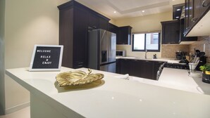 A modern kitchen with dark cabinetry, stainless steel appliances, and a white countertop. - D&D Divine Suite
Ocho Rios, St. Ann Parish (Ocho Rios)