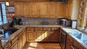 A kitchen with wooden cabinets, granite countertops, a stainless steel sink, and a built-in toaster.