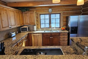 Una cocina con armarios de madera, encimera de granito, refrigerador de acero inoxidable y estufa integrada.
