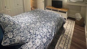 Ein Schlafzimmer mit einem Bett, einem Fernseher, einem Fenster und einer Tür.