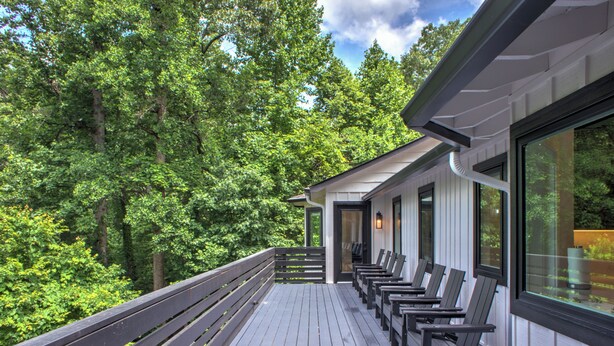 Eine überdachte Terrasse mit Holzbänken und Blick auf einen Wald.