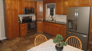 A kitchen with wooden cabinets, stainless steel appliances, and a small table with chairs.