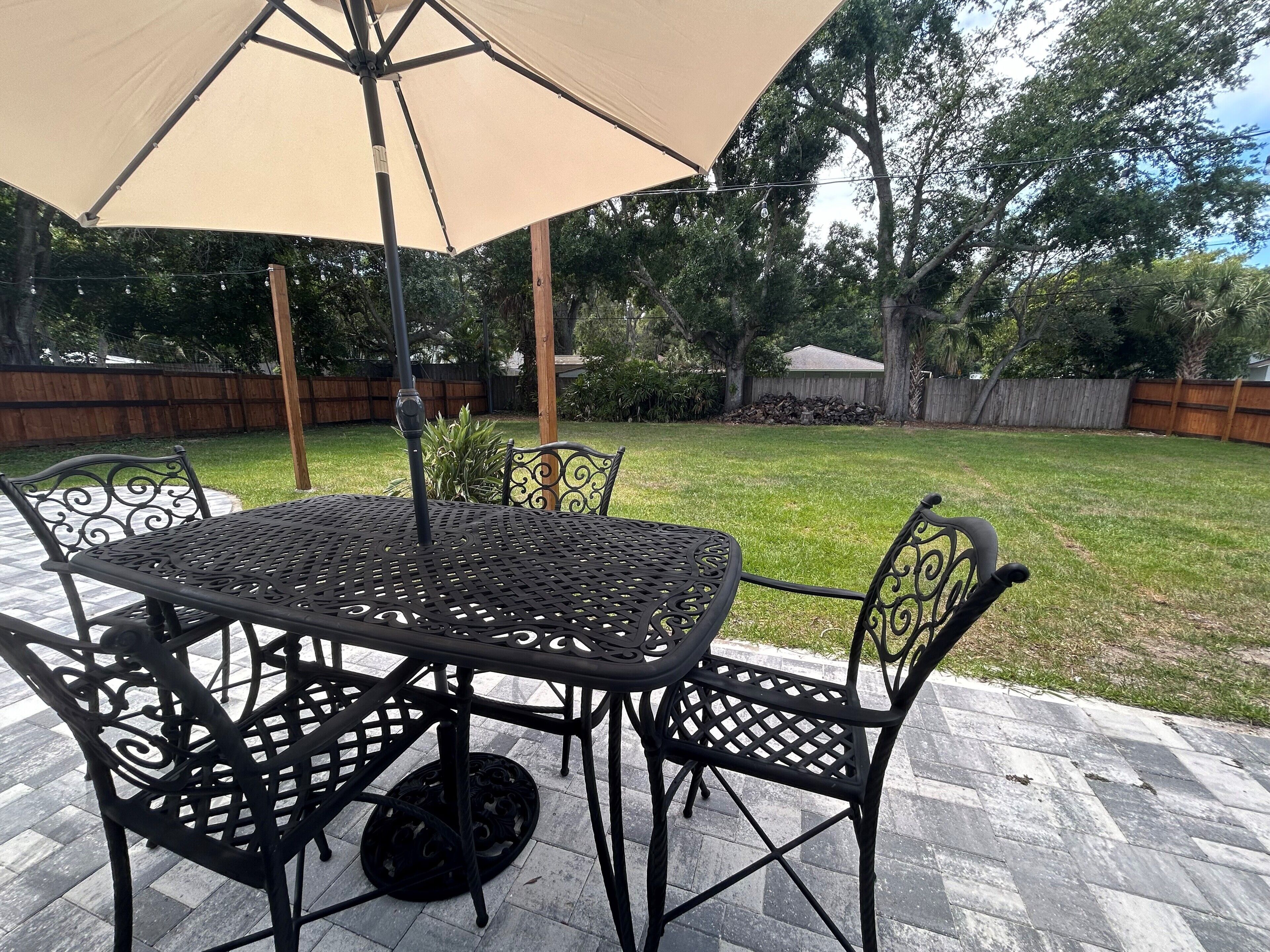 Eine Terrasse mit Tisch und Stühlen unter einer Markise, umgeben von einem Holzzaun und Grünpflanzen.