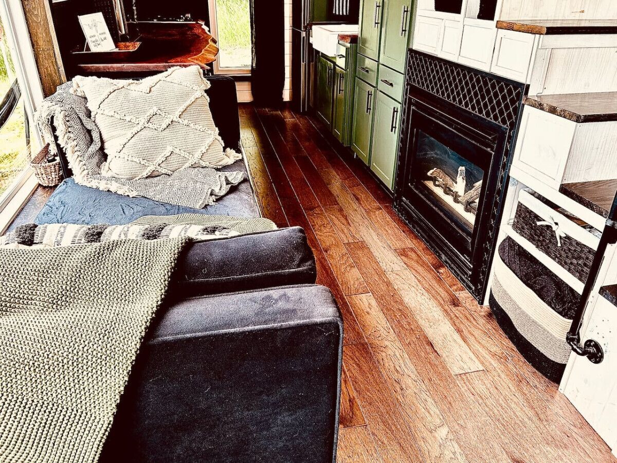 Un salon chaleureux avec une cheminée, un plancher en bois et des meubles de couleur verte.