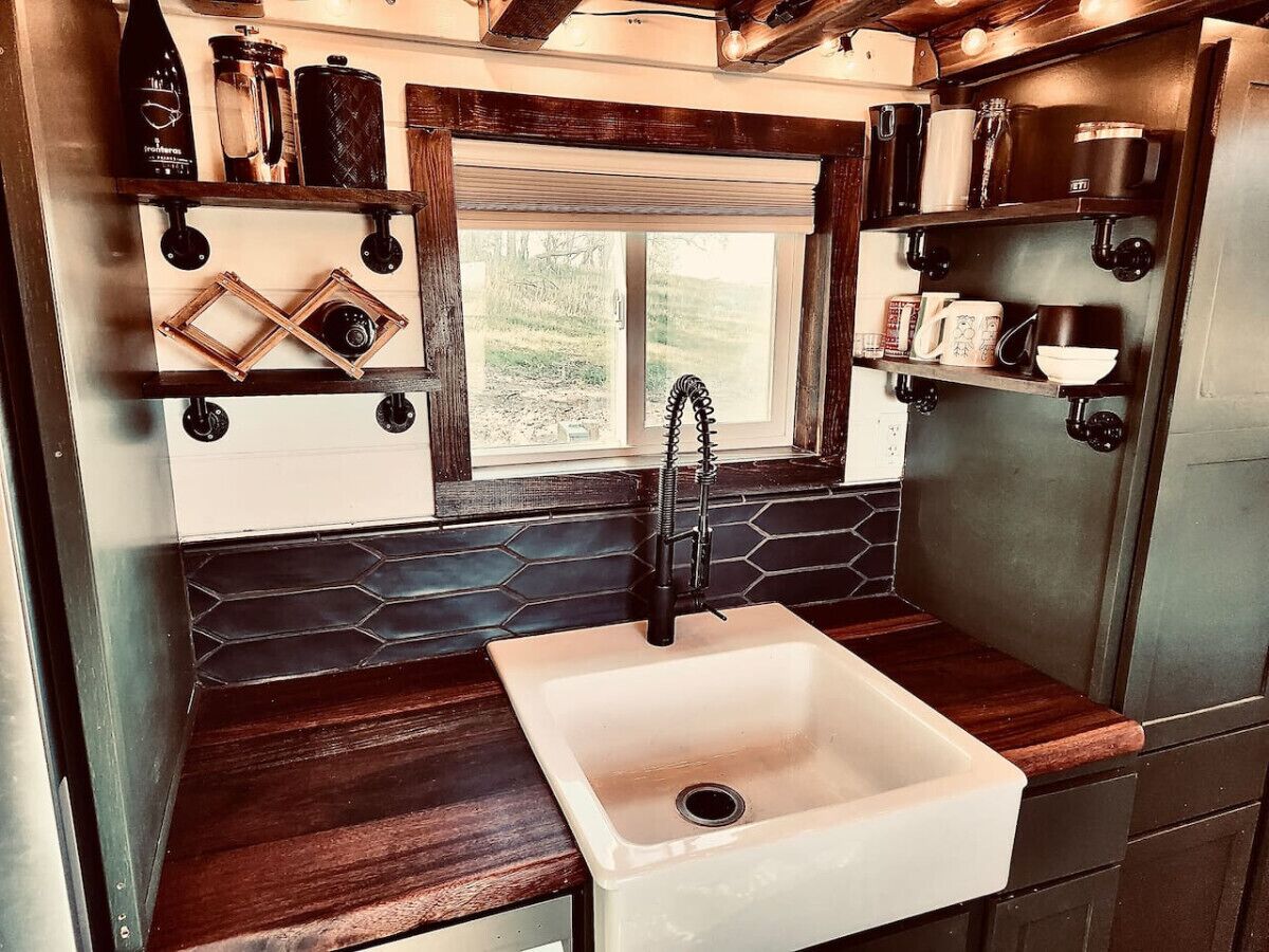 A compact kitchen with a white sink, wooden countertops, and a hexagonal backsplash.