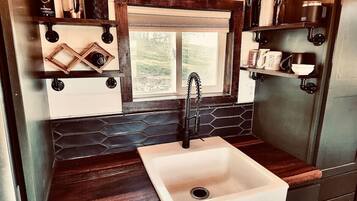 A compact kitchen with a white sink, wooden countertops, and a hexagonal backsplash.