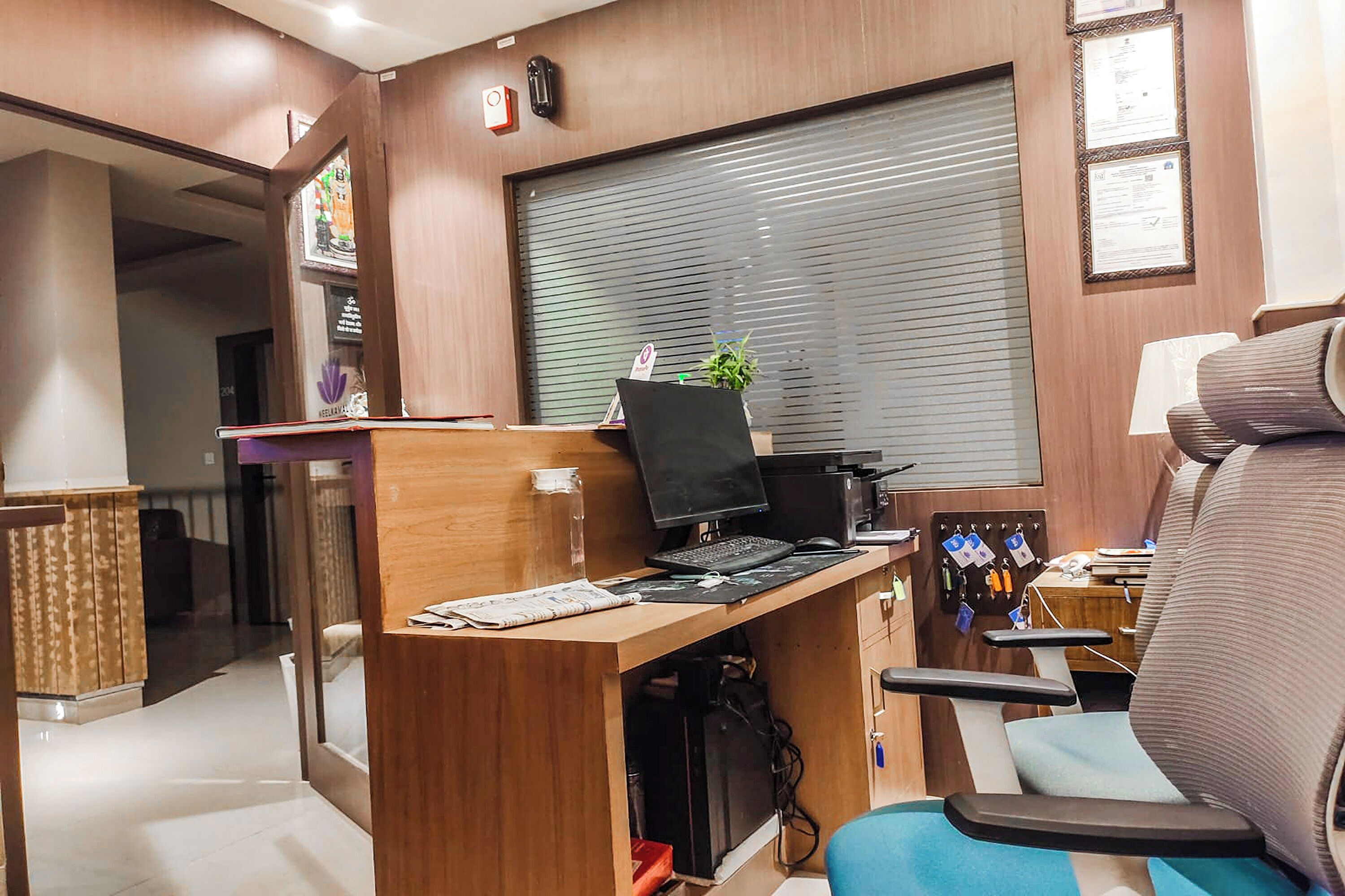 A modern office space with a wooden desk, computer, and a blue chair.