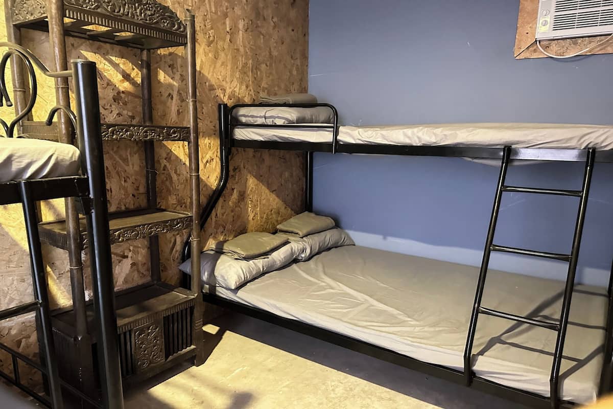 Une chambre avec un lit superposé, un mur en bois et une fenêtre.