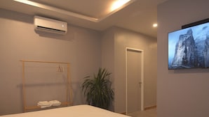 A modern hotel room with a large bed, an air conditioning unit, a wardrobe, a potted plant, and a framed picture on the wall. - Mosaic Liwliwa Hotel Near Beach (San Felipe)