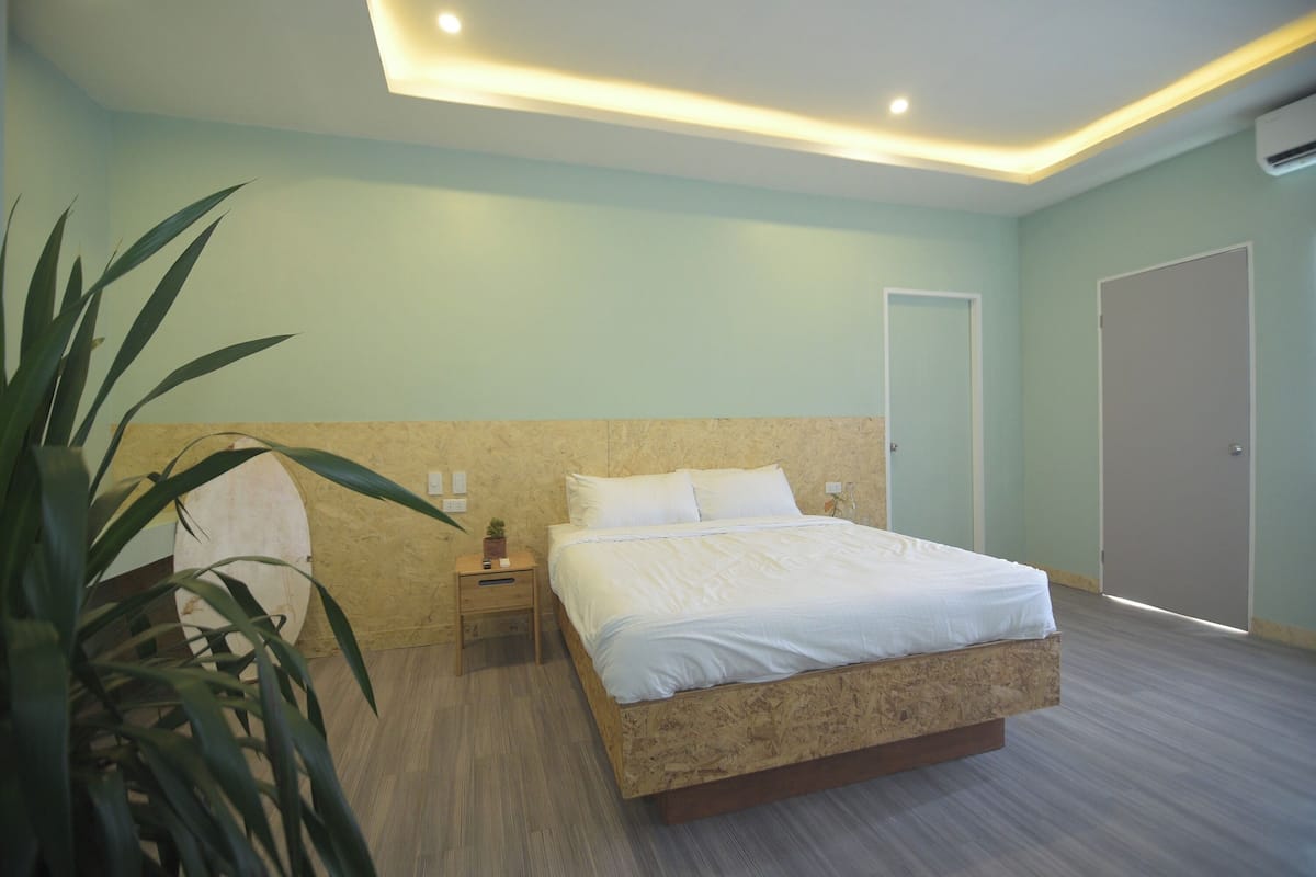 Une chambre à coucher avec un lit, une table de chevet, une commode et une plante en pot.