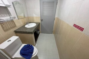 A small bathroom with a toilet, sink, and mirror. There is a sign on the wall indicating the toilet is for women.