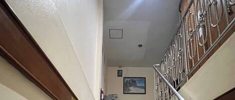 Una escalera de piedra con barandales de metal que conduce a una zona de recepción con un mostrador y un cuadro en la pared.