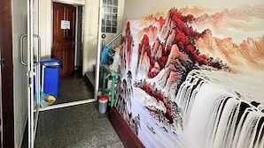 A hallway with a large painting of a waterfall, a staircase, and a door leading to another room. - One World One Home Patong 1 (Patong)