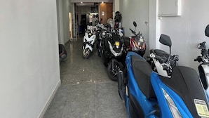 A narrow hallway with several motorcycles parked on the right, leading to a room with a visible door at the end. - One World One Home Patong 1 (Patong)