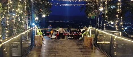 An outdoor dining area with string lights, wooden tables, and chairs.