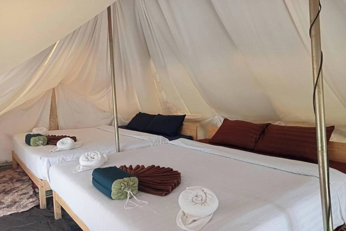 Een tentkamer met twee bedden, elk voorzien van netjes opgemaakte handdoeken en kussens.