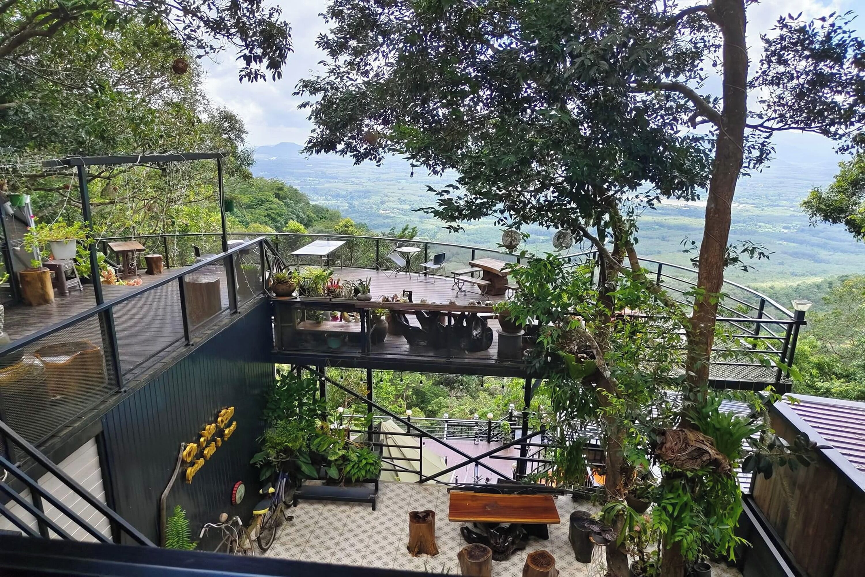 A multi-level outdoor terrace with seating and dining areas, surrounded by lush greenery and offering scenic views.