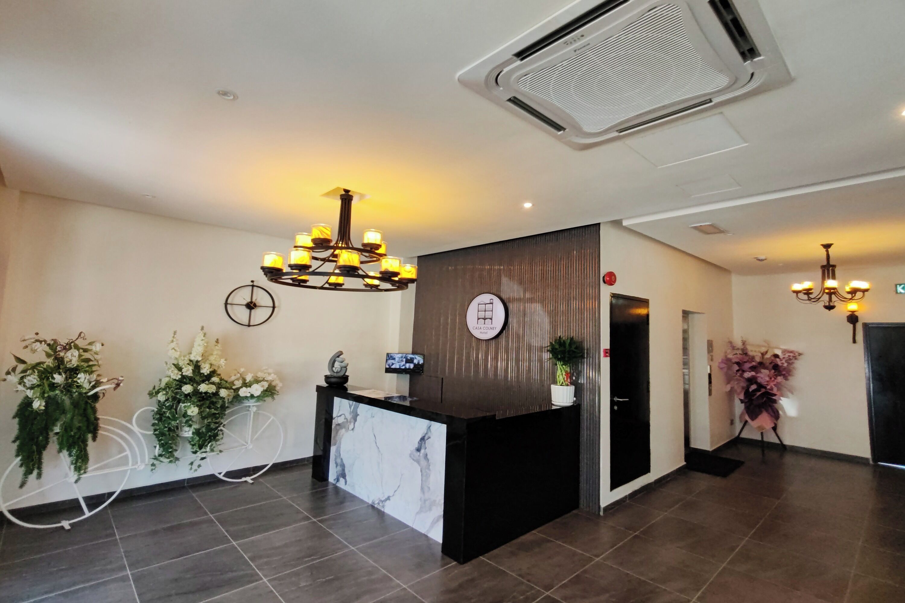 A reception area with a marble counter, a wall-mounted clock, and a chandelier.