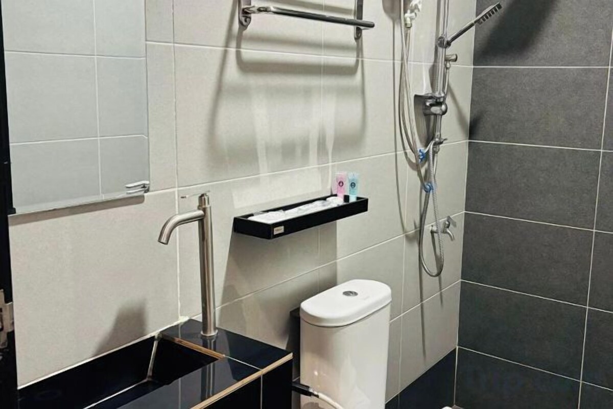 A modern bathroom with a black sink, a white toilet, and a shower area.