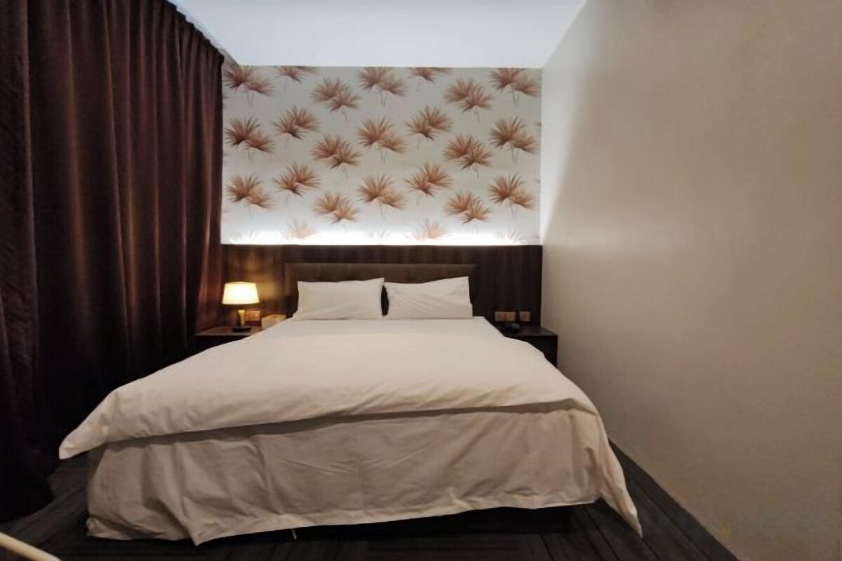 A hotel room with a bed, a nightstand, a lamp, and a patterned wall.