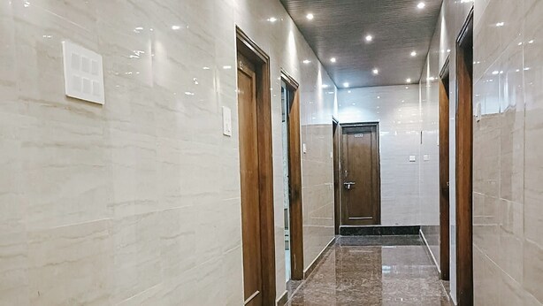 Un pasillo con paredes de mármol y suelo de piedra pulida, que conduce a una puerta al final.
