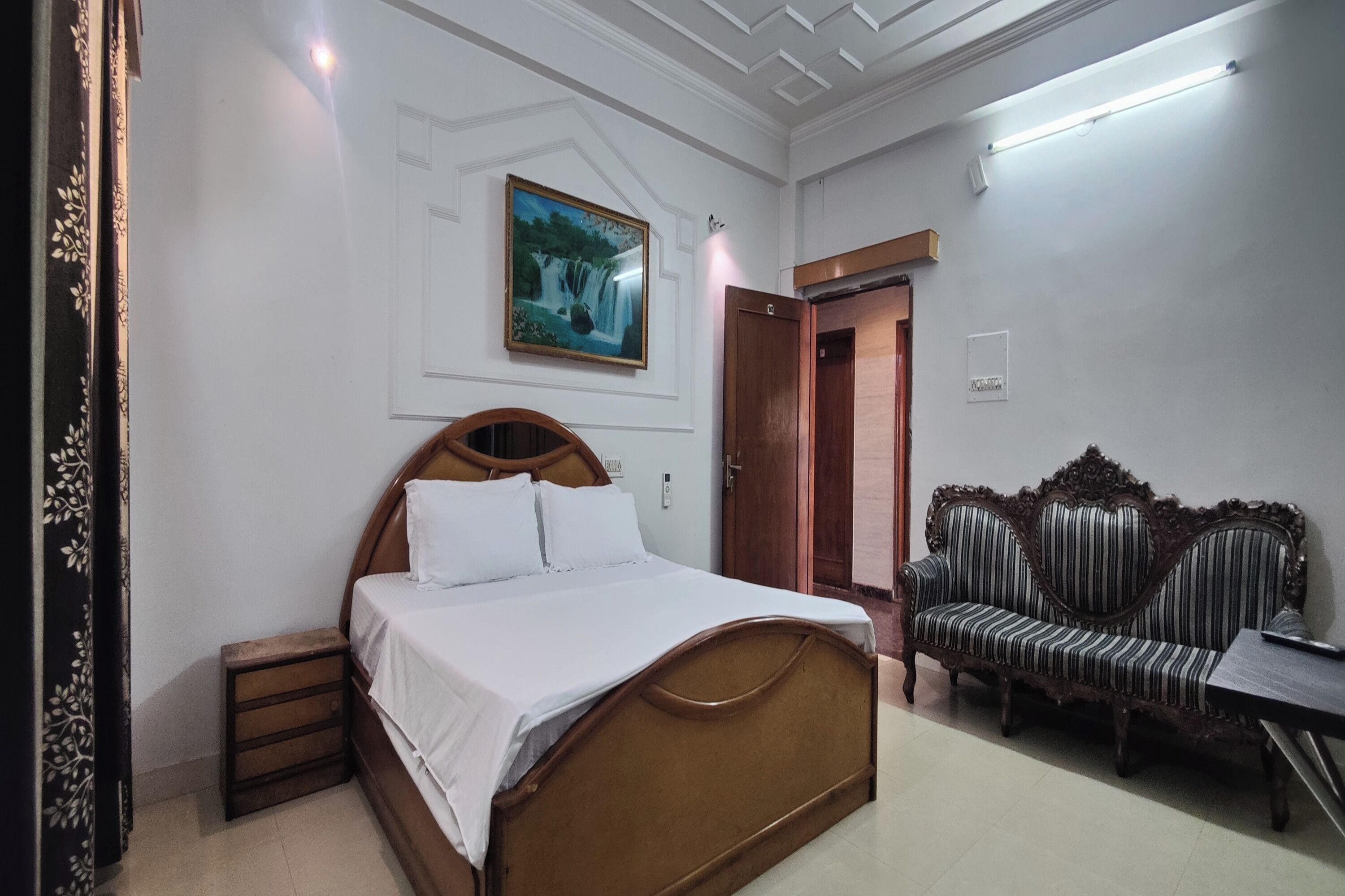 Un dormitorio con cama, sofá, mesita de noche y un cuadro en la pared.