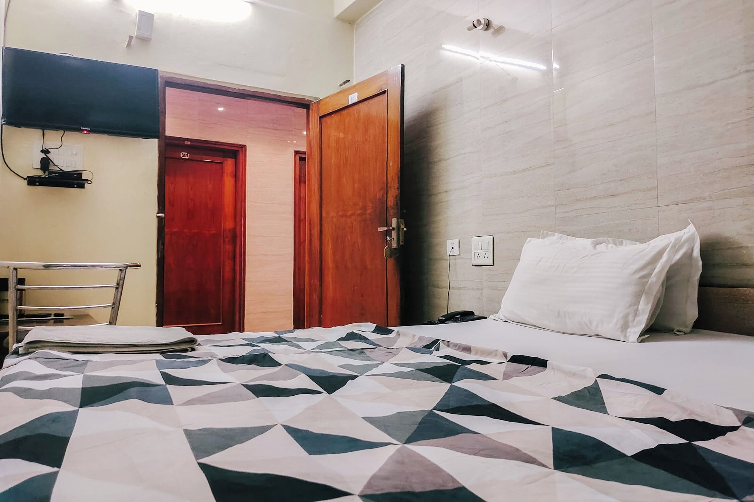 Une chambre d’hôtel équipée d’un lit, d’un bureau et d’un téléviseur fixé au mur.