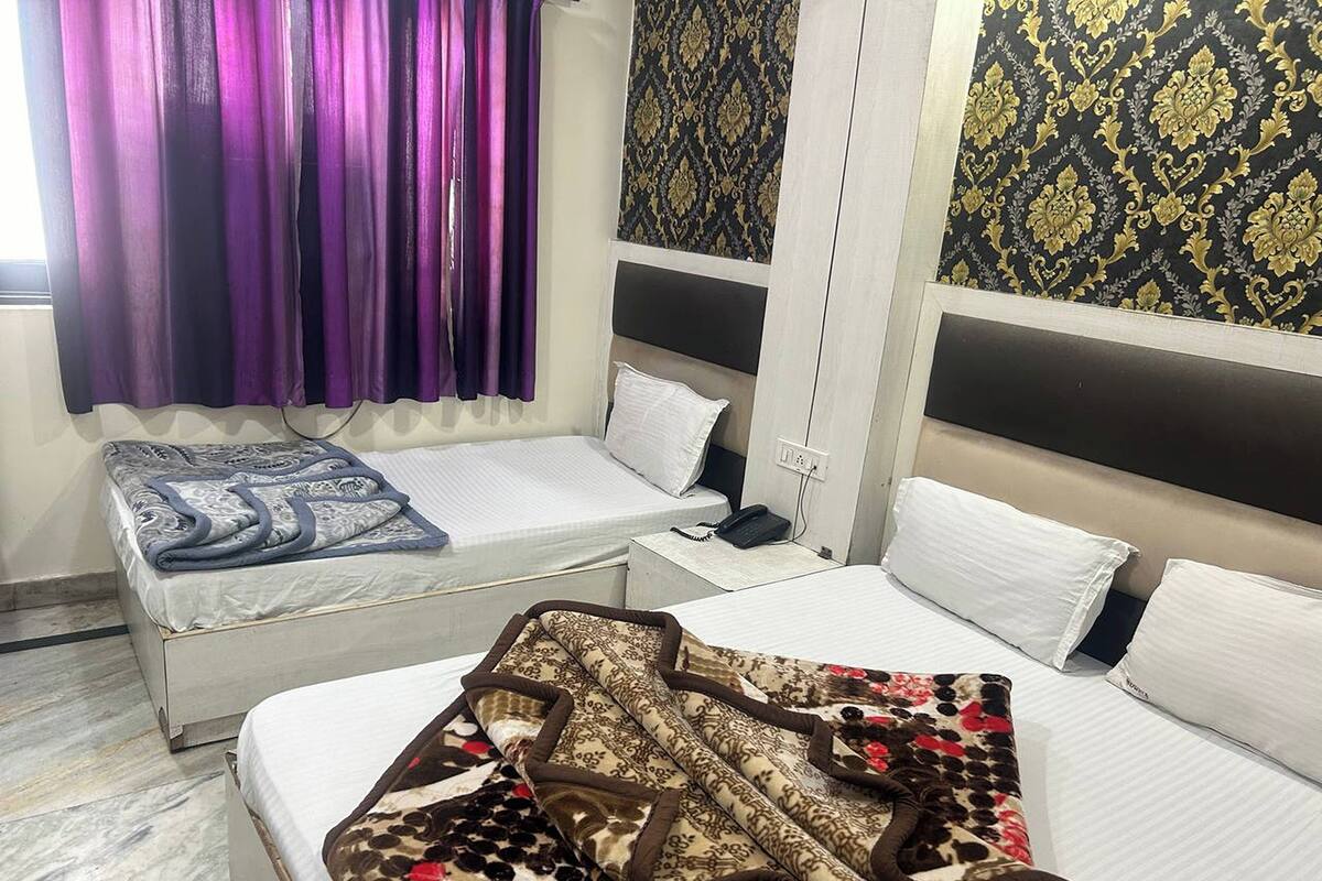 Ein Hotelzimmer mit zwei Einzelbetten, einem kleinen Tisch, einem Telefon und violetten Vorhängen.
