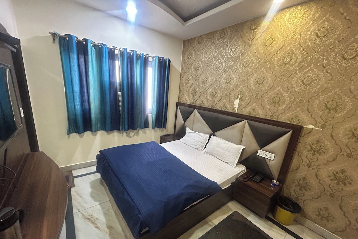Ein ordentlich eingerichtetes Schlafzimmer mit Bett, Vorhängen, Nachttisch und einer Wand mit Musterdesign.
