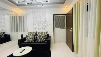 A modern room with a black sofa, a white round table, and a large mirror.