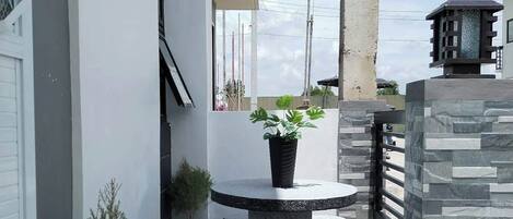A modern outdoor patio with a round table, potted plants, and a stone wall.