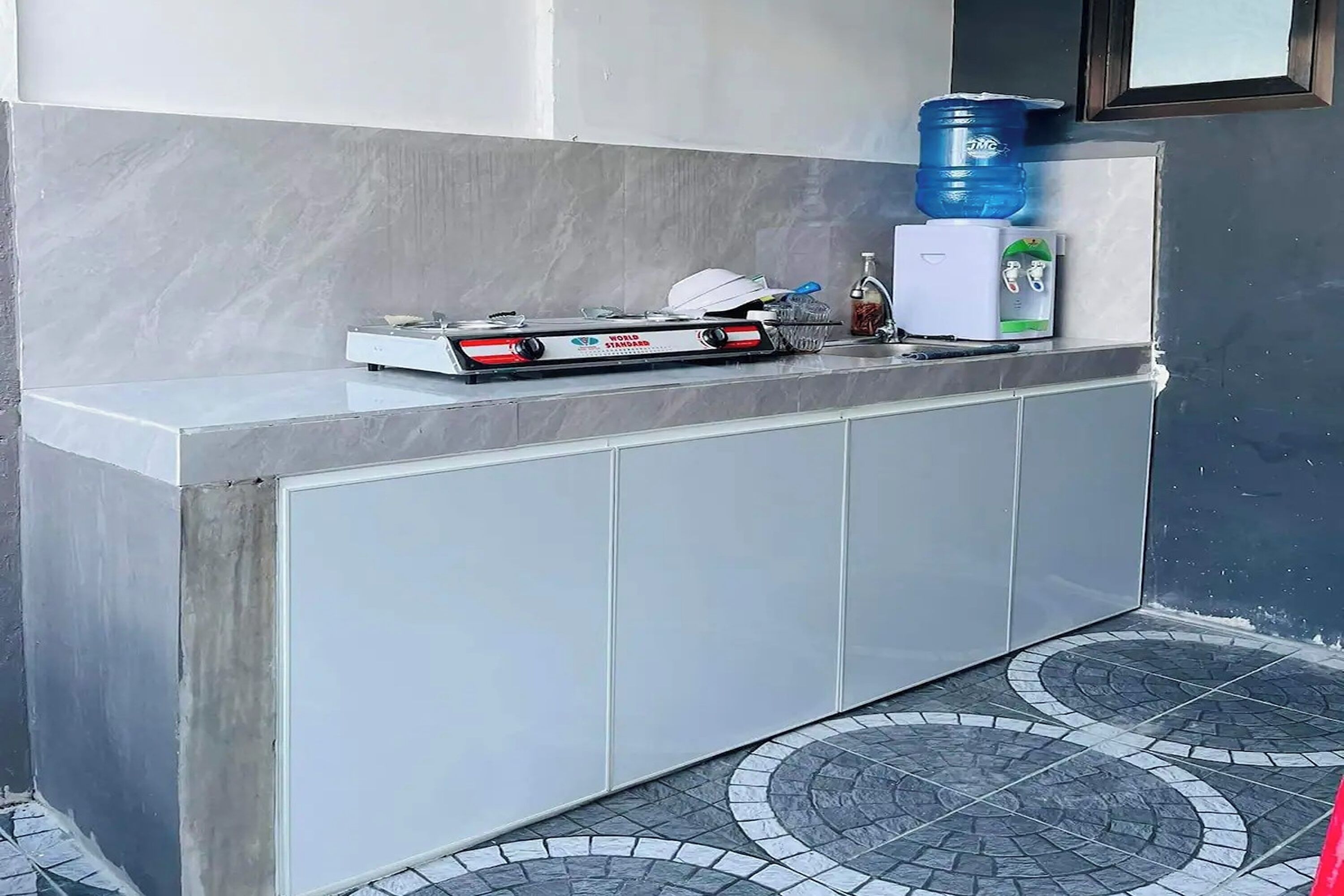 Angolo cottura con piano cottura a gas, dispenser d'acqua e lavello.