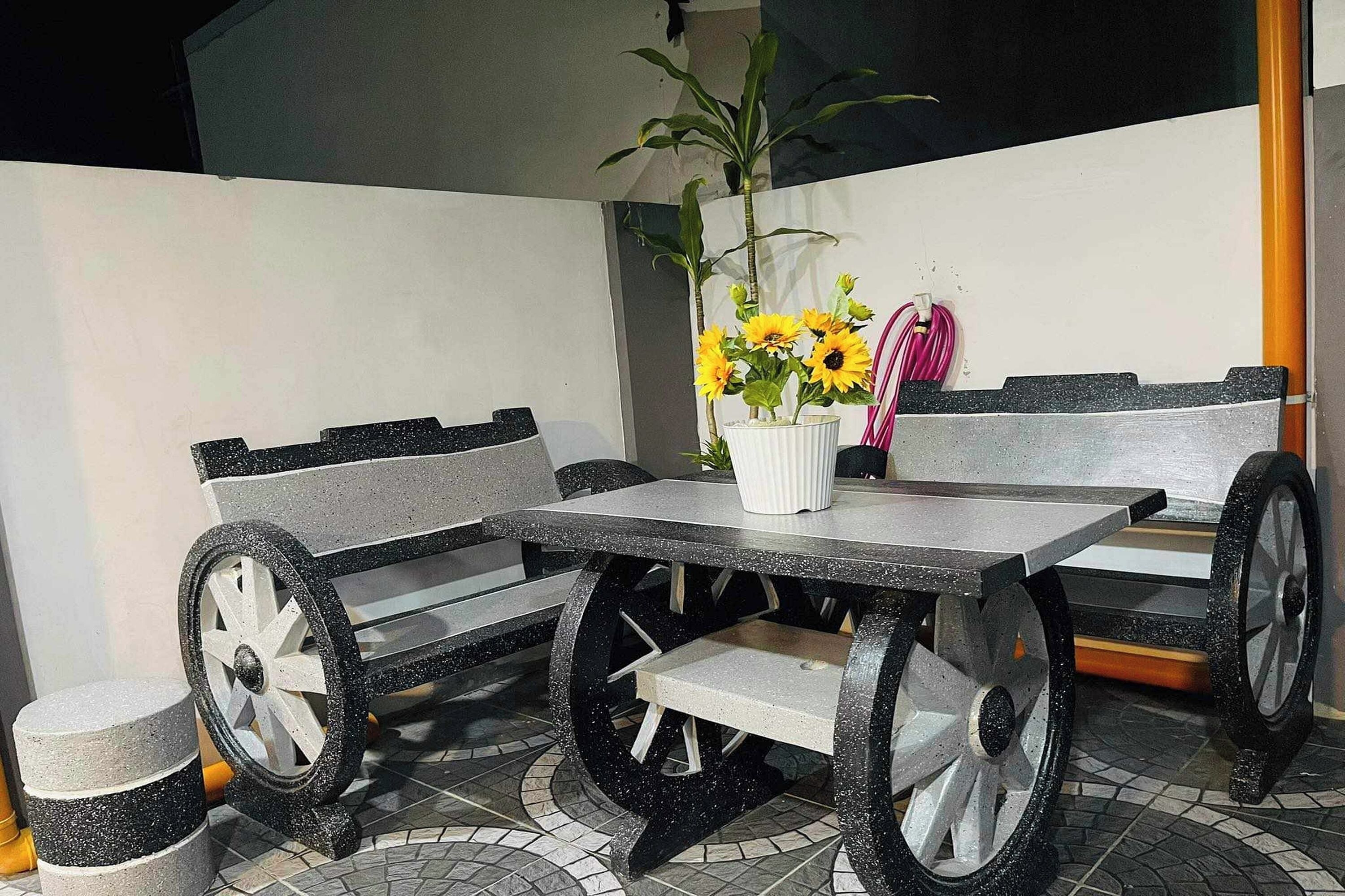 A table and bench set with a potted plant and a pink cloth.