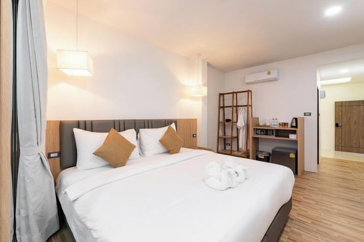 A hotel room with a large bed, a wardrobe, a desk, and a mirror.