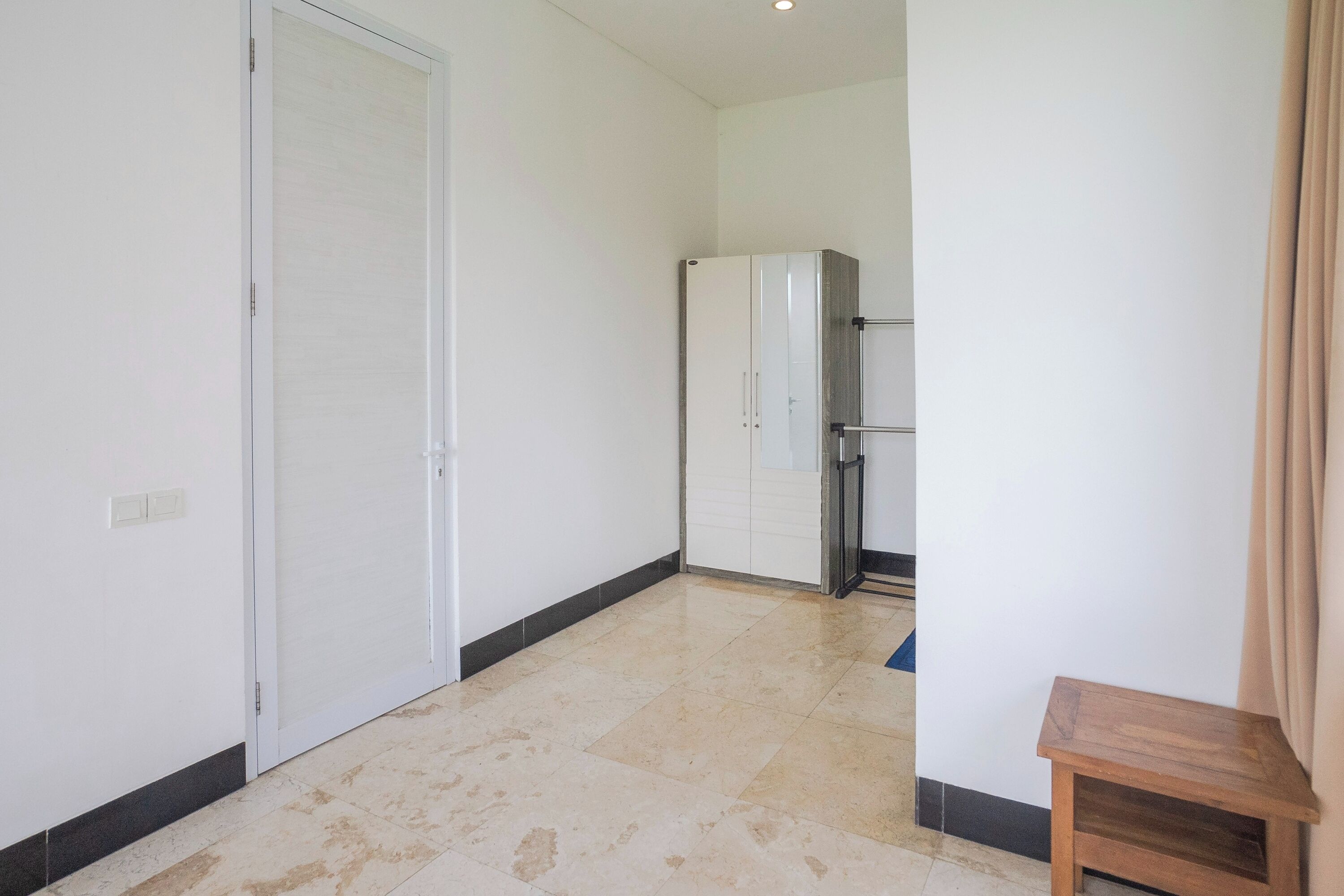 A corridor with a closed door, a wardrobe, and a small wooden table.