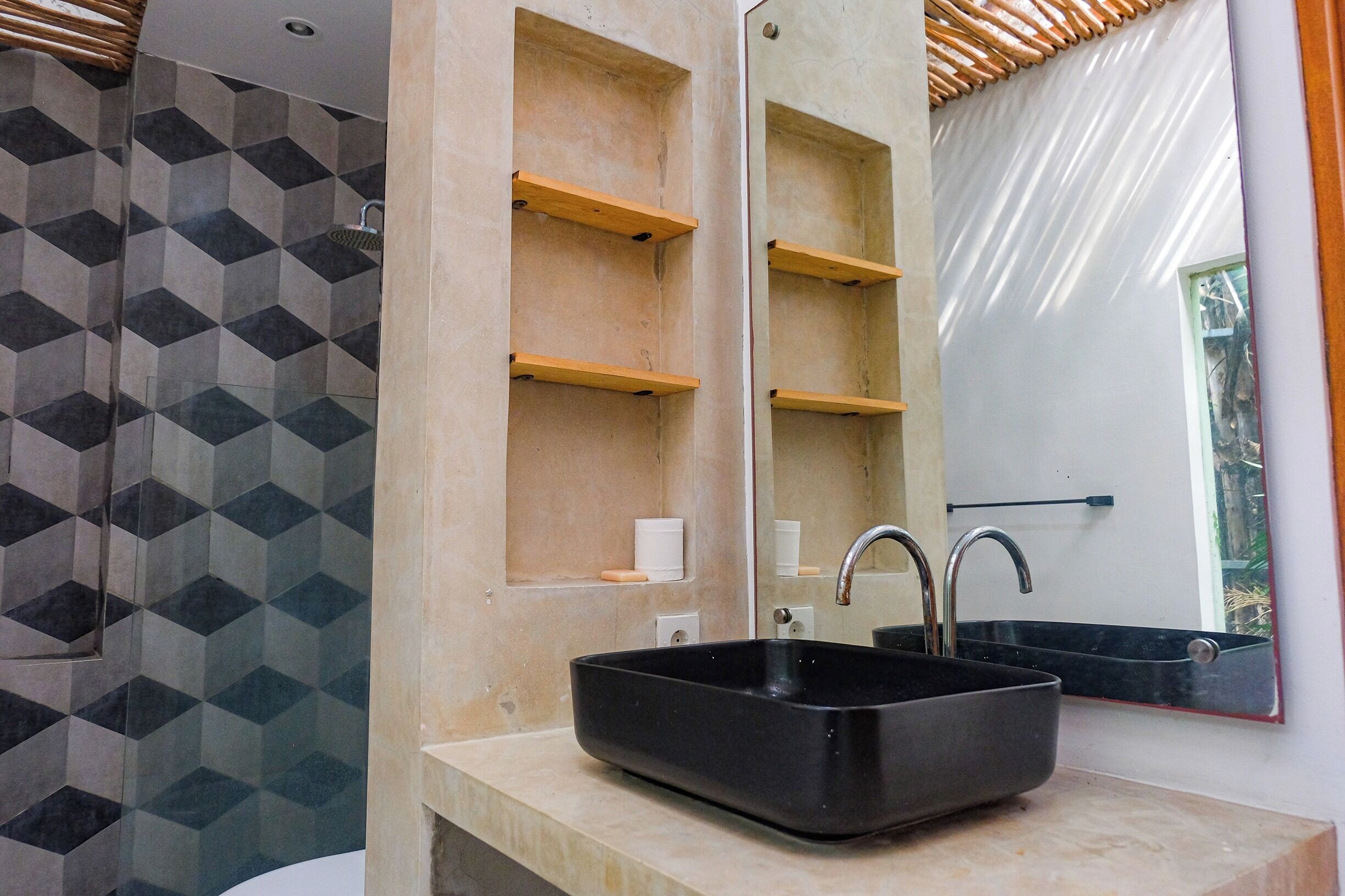 A bathroom with a black sink, a mirror, and a geometric patterned wall.