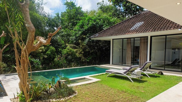 A modern house with a swimming pool, a glass door entrance, and a well-maintained lawn.