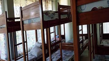 A room with bunk beds, a window with floral curtains, and a bed with a pillow.