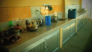 A kitchen with a long countertop, a sink, and various kitchen items like pots and a kettle. - Awel Seashore Inn Baler (Baler)