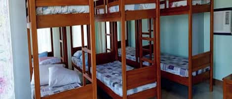Una habitación con cuatro literas de madera, cada una con colchón y almohadas.
