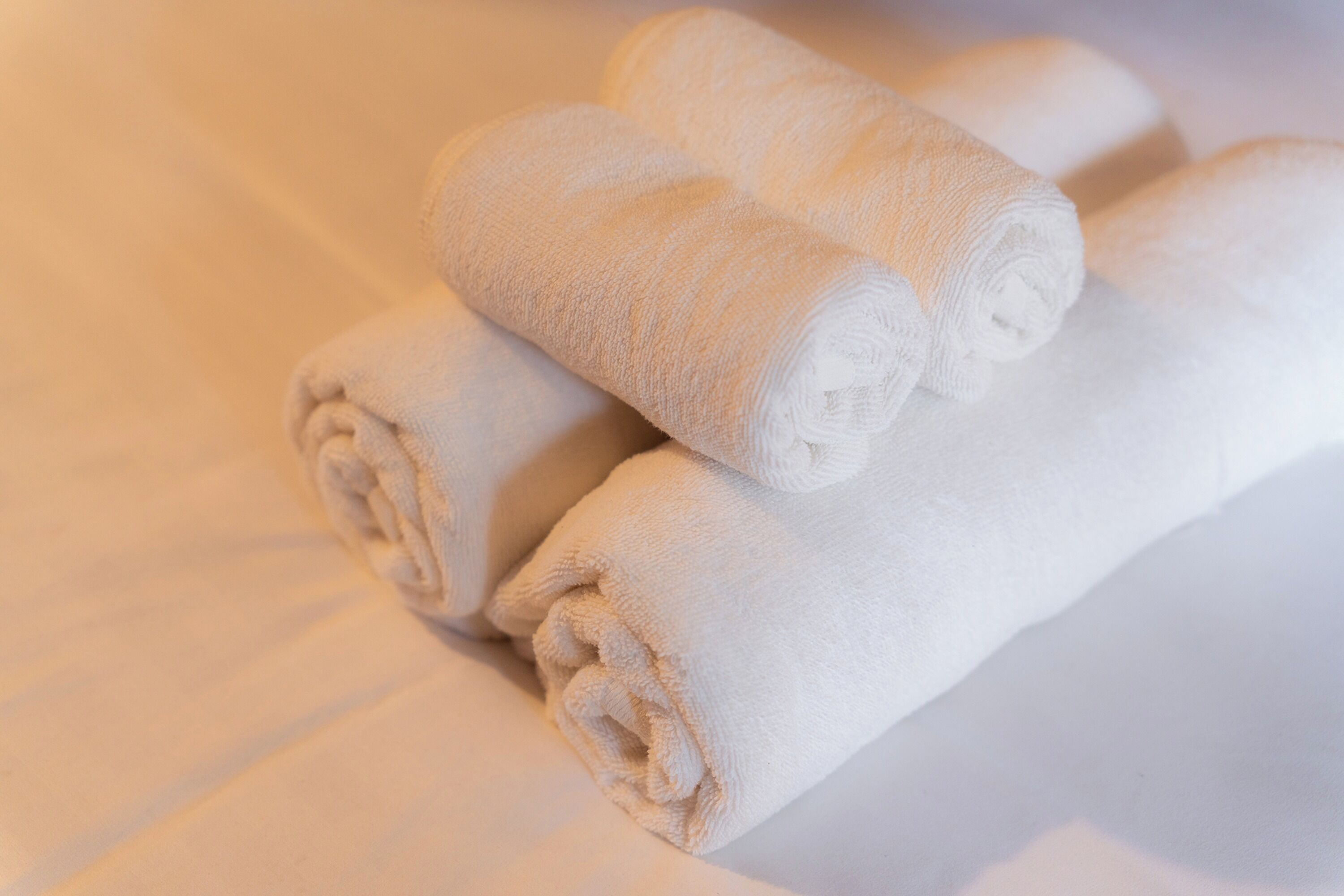 Des serviettes blanches, soigneusement enroulées, sont empilées sur un lit.