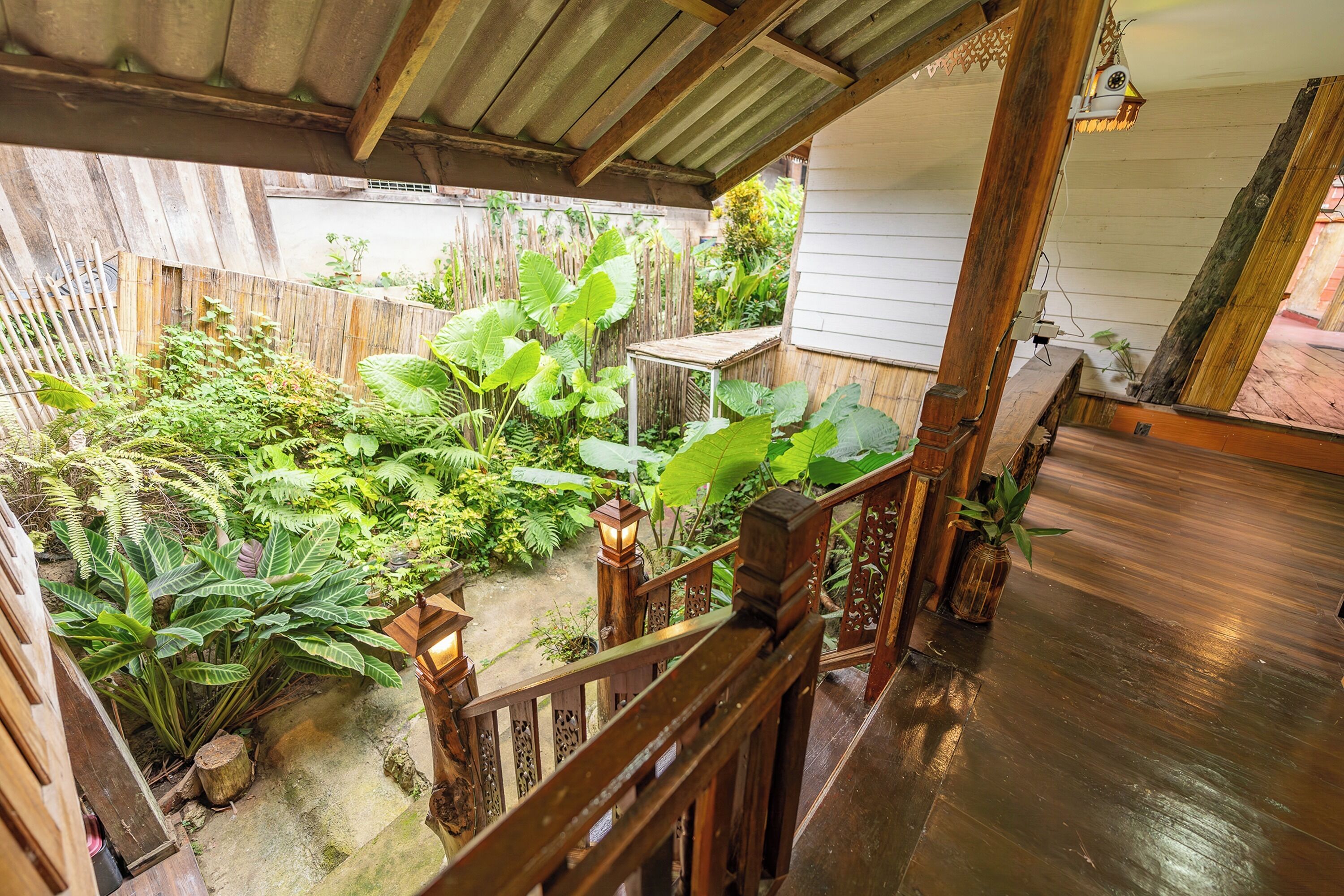 Una escalera de madera que lleva a un espacio exterior cubierto con una valla de madera y diversas plantas.