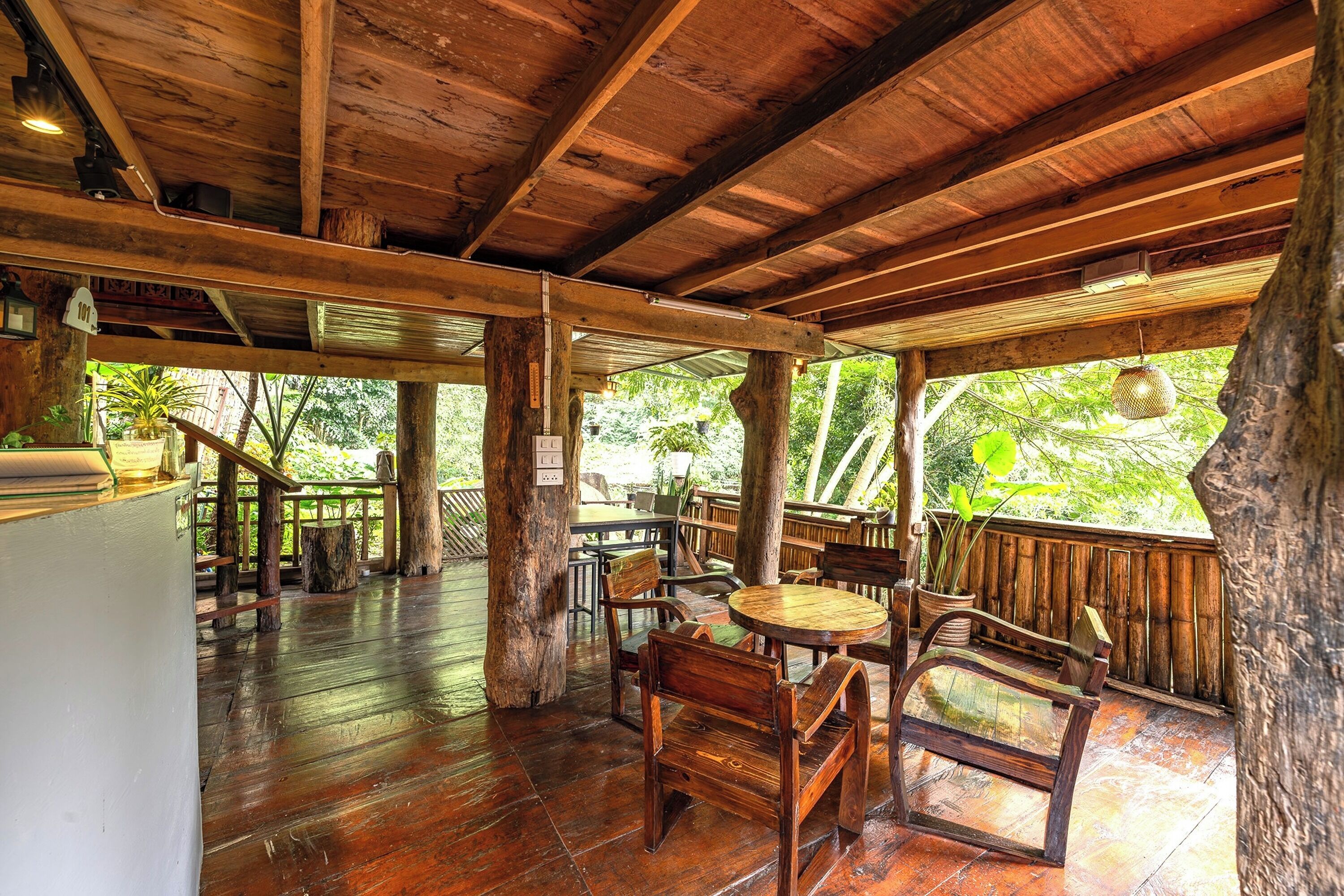 A wooden deck with a rustic design, featuring a round wooden table and several wooden chairs.
