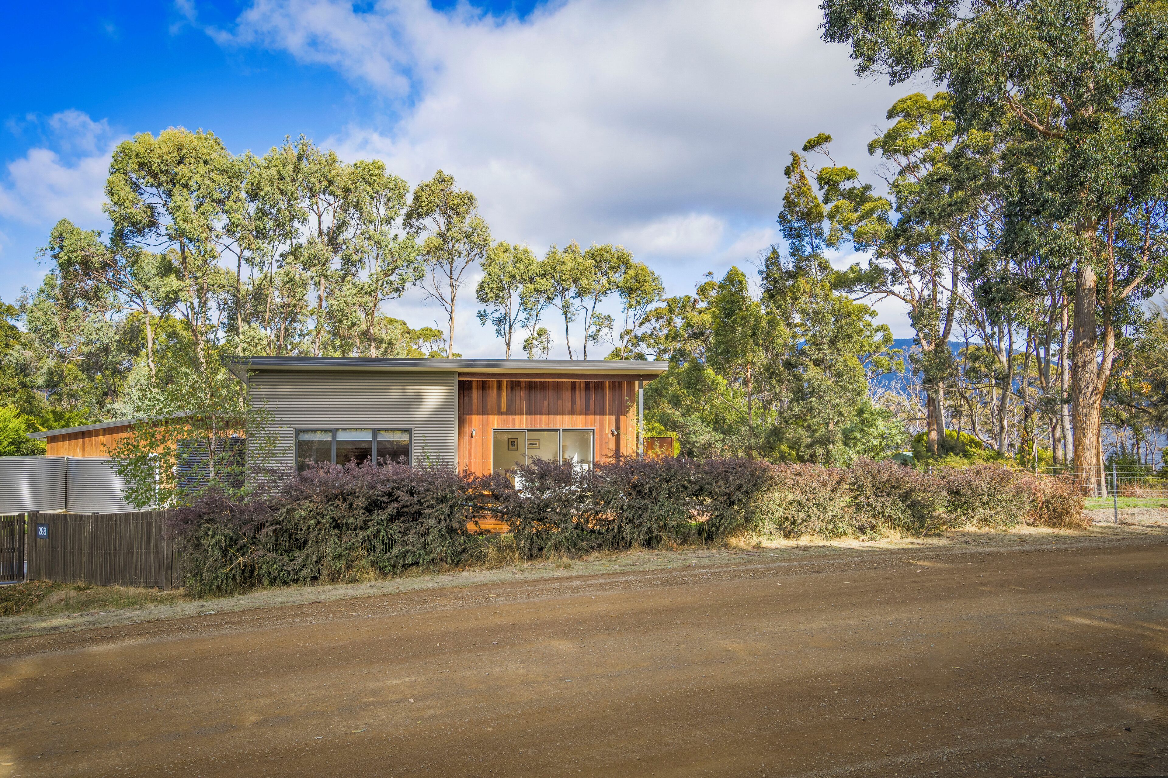 A modern two-story house with a wooden deck and a fenced yard.