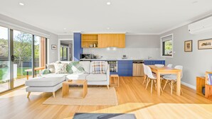 Un espacio moderno y abierto que combina sala y comedor, con cocina, ventanas amplias y vistas al exterior.