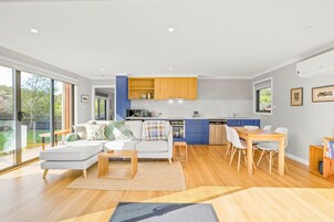 Un espacio moderno y abierto que combina sala y comedor, con cocina, ventanas amplias y vistas al exterior.