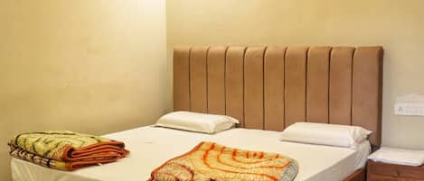 Une chambre à coucher comprenant un lit, un ventilateur de plafond, un appareil de climatisation et une table de chevet.