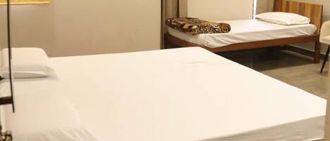 A hotel room with two single beds, a wooden headboard, a purple rug, and a lamp.